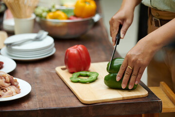 Hands of woman cutting bell pepper to grill outside