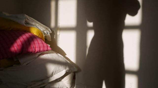 Shadow of a woman on white wall changing clothes in the room
