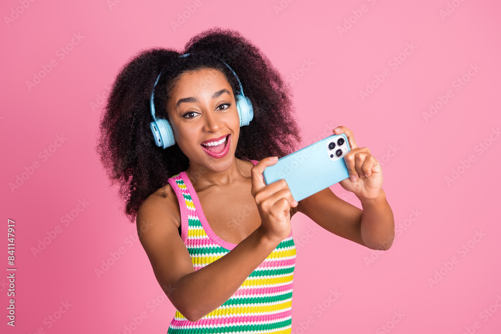 Poster Photo of nice woman with perming coiffure dressed knitwear tank in headphones take shoots on smartphone isolated on pink color background