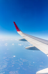 Fototapeta premium View from the airplane window at a beautiful cloudy sky and the airplane wing