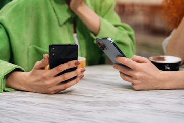 Two friends enjoying coffee date with smartphones in hand