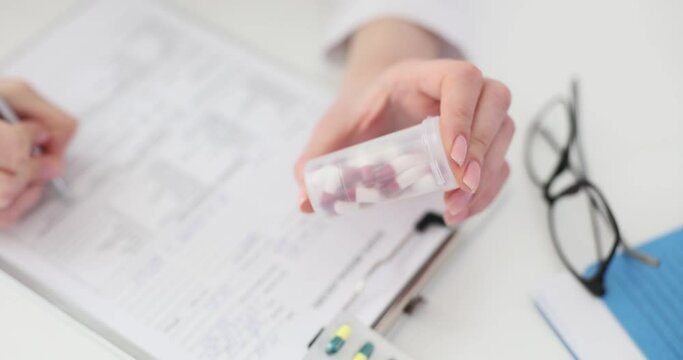 Doctor holding a bottle of pills and writing a prescription