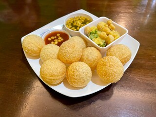 Pani puri is a deep-fried breaded hollow spherical shell, filled with a combination of finely diced potato, onion, peas and chickpea. It is a common street food in the Indian subcontinent