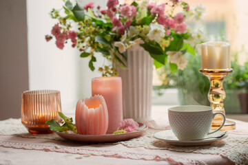 cup of tea with burning candles and pink roses at the window