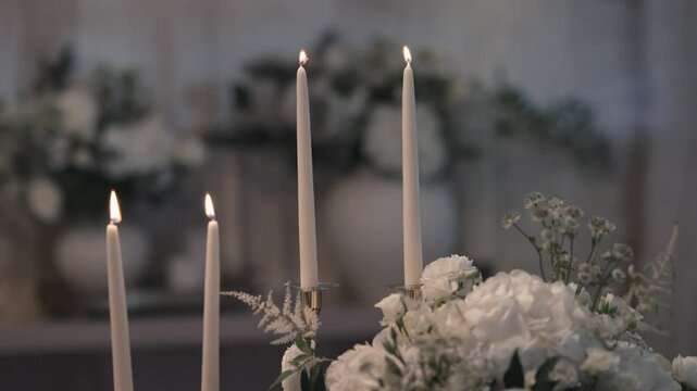 Lit taper candles and white floral arrangement creating an elegant and romantic atmosphere.