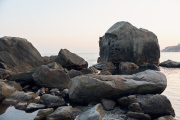 Serene sunset view of rocky shoreline with massive boulders in the foreground by the water