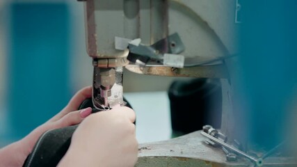 Worker punching holes for laces in a shoe during production in a factory.