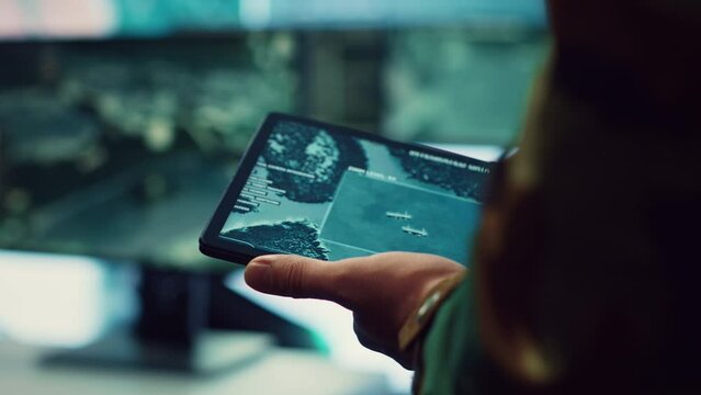 Navy operations specialist following hostile warship trajectory around the national waters, working on ensuring protection via satellite radar system on a tablet. IT professional. Close up. Camera A.