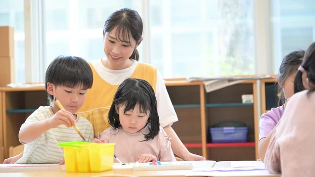 学童や放課後デイサービス等で絵を描く勉強をする先生と生徒　小学生複数と見守る先生の動画
