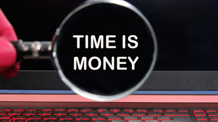 Stock market concept,TIME IS MONEY written text appeared through a magnifying glass on a dim laptop...