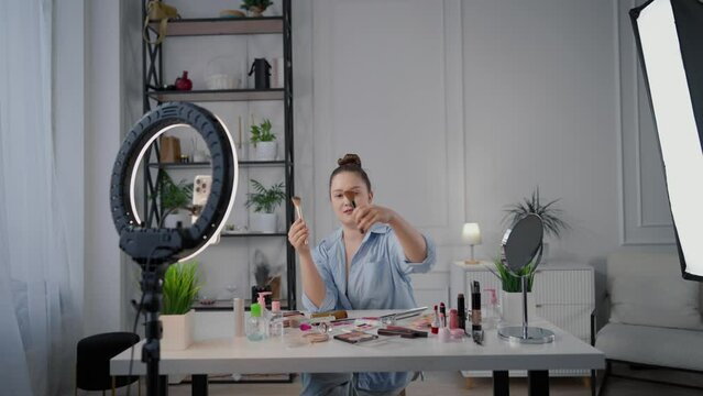 Beauty blogger woman filming review on cosmetic brushes in home studio, stream. Influencer of beauty industry demonstrating new brushes for makeup, native advertisement for followers in social media