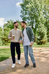Obraz premium A happy, bearded gay couple walks hand-in-hand through a lush green park on a sunny day.