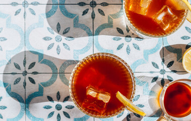 Trendy summer drink espresso tonic on blue tile background with shadow of sun. Cold coffee cocktail in summer sunny day. Coffee menu. Top view