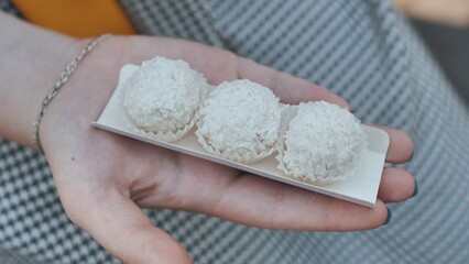 The girl is eating round white coconut candy.