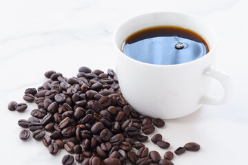 淹れたてで香りのよいコーヒーが入ったカップと、コーヒー豆
