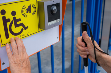 Close-up of the hands of a blind elderly woman reading a text in braille. Button for calling help...