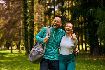 Obraz premium Happy athletic couple laughing while exercising together in park.