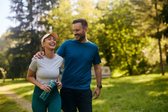 Happy couple laughing while working out in park.