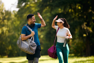 Cheerful athletic couple giving high-five after successful workout in nature.