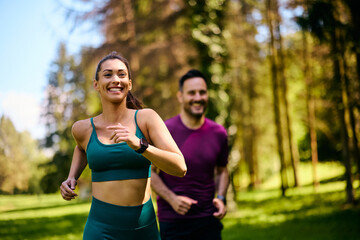 Happy athletic woman running with her friend in park.