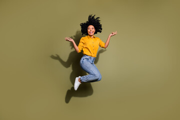 Full length portrait of pretty lady jump have fun wear yellow shirt isolated on khaki color...