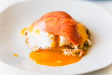 Poached egg with salmon on a white plate on a light background. Selected focus.