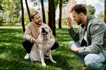 Two bearded men, a gay couple, enjoy a sunny day in a green park, laughing and playing with their labrador retriever.