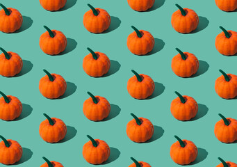 Trendy autumn or fall pattern made with orange pumpkins on green background. Minimal autumn composition. Nature flat lay. Season concept. Pumpkin aesthetic.