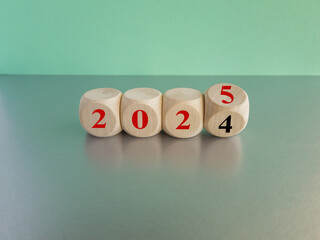 2025 number of with change to new era concepts. Flipping the 2024 to 2025 year calendar numbers on wooden dice, cube blocks isolated on blue background, minimalist simple style