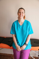 A woman in a blue scrubs shirt is smiling
