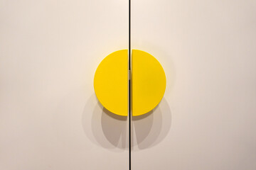 closed white wardrobe with wooden doors and yellow metal handles in dressing room, modern furniture at home, storage concept     