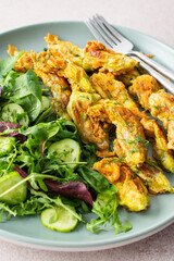 Fried zucchini flowers in batter and mix salad with cucumbers close up