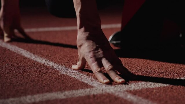 Sportsman Training In Stadium In Night, Closeup View Of Male Hands On Run Lane, Low Start Position