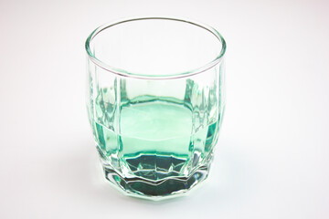 Glass with light green,aquamarine alcoholic beverage on white background.