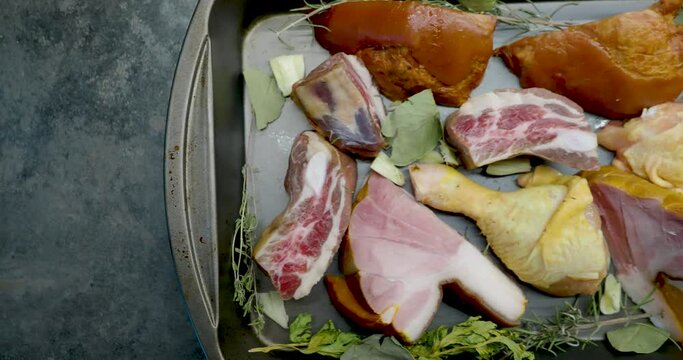 Raw uncooked pork meat and chicken on a tray with spices and vegetables