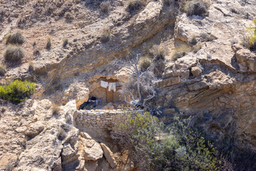 Photo of a strange door and house in the cliffs of Benidorm in Spain showing the door and washing hung out on the line and a dry brick wall