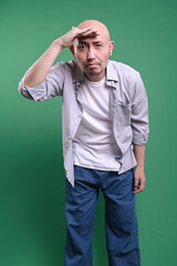 Fototapeta premium Adult Asian Bald Man Looking Far Away At Distance With Hand Over Head