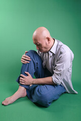Fototapeta premium Adult Asian Bald Man Siitng On Floor And Massaging Sore Leg With Painful Expression
