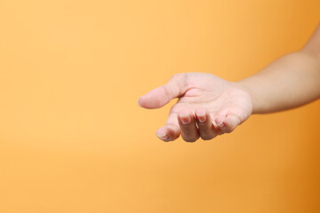 Female hand keeping empty cupped palm isolated on yellow background. Offering or begging concept. 