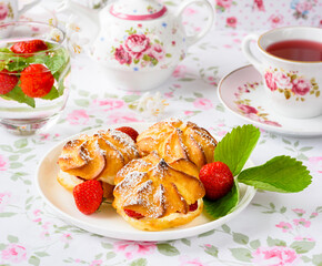 Cream puffs cakes or profiterole filled with whipped cream served with strawberries