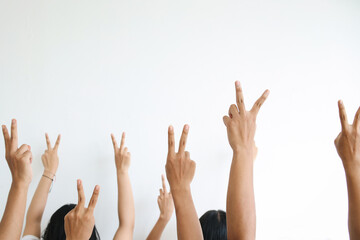Diverse multiethnic people raise hands up in the air showing peace hand sign