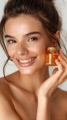 Fototapeta premium Beautiful smiling young woman with clean skin holding facial essential oil or serum with dropper, rejuvenation and skin care, white background