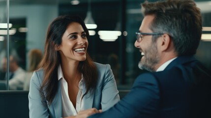 A man and a woman sit together at a wooden table, engaged in conversation - Powered by Adobe