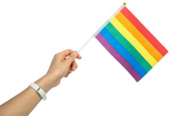 Someone hand holding a rainbow flag during a PRIDE month. The rainbow flag is a symbol of lesbian, gay, bisexual, transgender and queer pride commonly used at LGBTQIA+ rights events worldwide.
