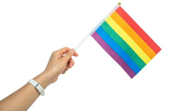 Someone hand holding a rainbow flag during a PRIDE month. The rainbow flag is a symbol of lesbian, gay, bisexual, transgender and queer pride commonly used at LGBTQIA+ rights events worldwide.