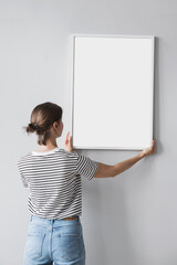 Woman holding blank wooden picture frame mockup on gray wall, Artwork mock-up in minimal interior...
