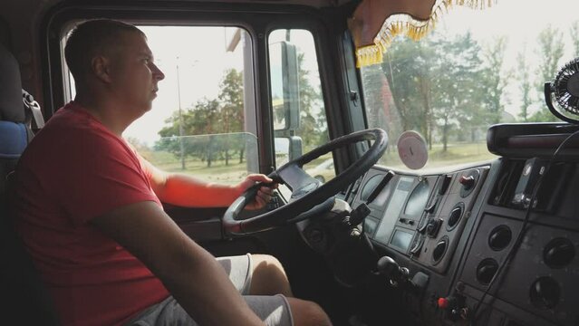 Trucker holding hand on a steering wheel and driving car at country road. Man shifting gears in a manual transmission and controlling truck. Lorry driver riding to destination. Logistics concept