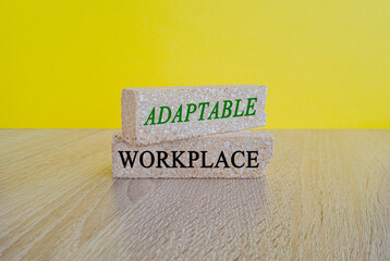 Adaptable workplace symbol. Concept words Adaptable workplace on brick block. Beautiful wooden table, yellow background. Business Adaptable workplace concept.