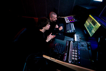 in the recording room dark With neon-lit studio, a sound recorder teaches his junior assistant how...