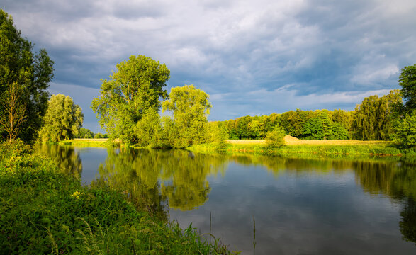 Ruhr River panorama near Schwerte and Iserlohn Germany. Colorful evening atmosphere in springtime on the shore of calm reflecting water of a barrage. Sunlit idyllic scenery after a may thunderstorm.